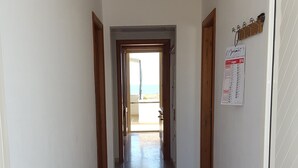 A hallway with a tiled floor, wooden doors, and a calendar on the wall. - holiday home 150 meters from the sea (Lido Marini)