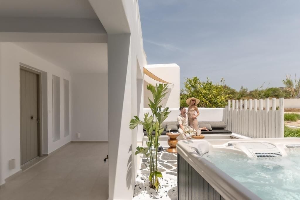 A modern outdoor area with a hot tub, seating, and a potted plant.
