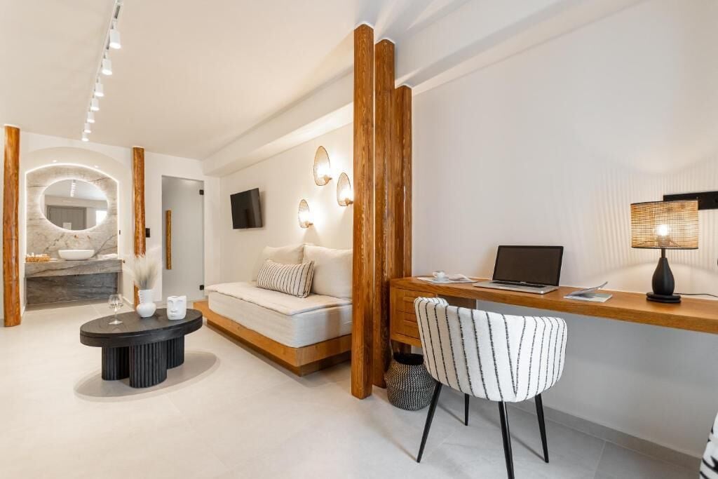 Een moderne woonkamer met een bank, een ronde salontafel, een houten bureau en een laptop.