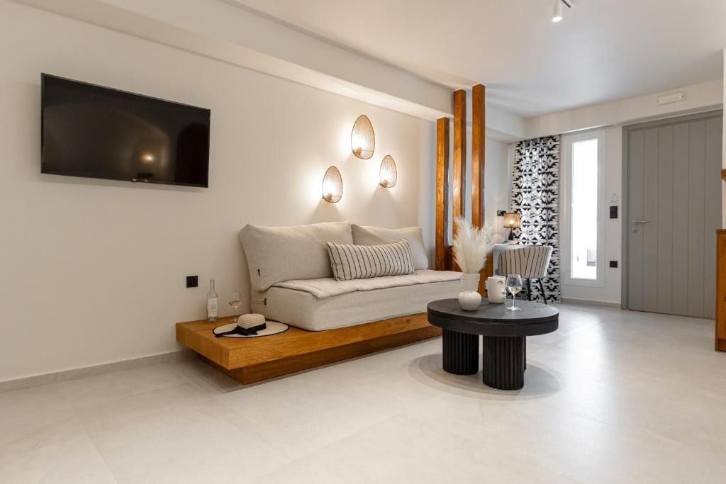 Een moderne woonkamer met een bank, een salontafel en een aan de muur bevestigde televisie.