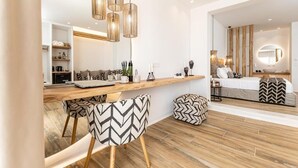 A modern living space with a wooden dining table, two patterned chairs, a sofa, and a bed. - Almiriki Naxos Beachside Living (Naxos)