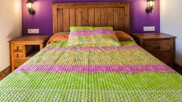 A bed with a colorful quilt, wooden headboard, and two nightstands with lamps.