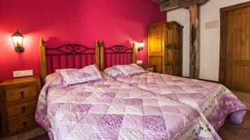 A bedroom with a large bed, wooden headboard, two bedside tables, and a wardrobe.