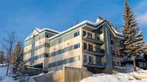Um hotel com vários andares e design moderno, com varandas e paisagem de estação de esqui.