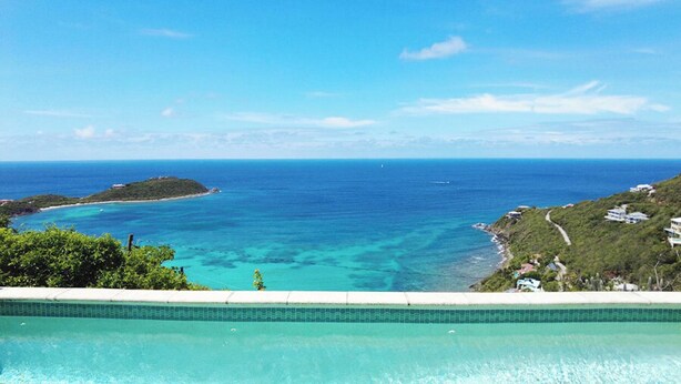 Une piscine avec vue sur une plage tropicale et l’océan.