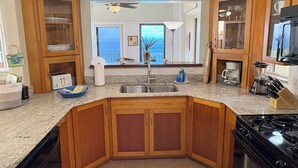 Une cuisine avec des meubles en bois, un plan de travail en granit, un évier et une cuisinière.