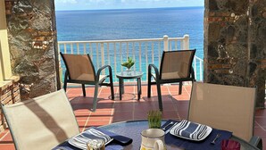 Une terrasse avec deux chaises, une petite table et une vue sur l’océan.