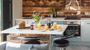 Eine moderne Küche mit einer Wand in Holzoptik, einer weißen Arbeitsplatte und einem eingebauten Backofen.