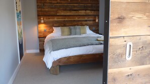 Ein Schlafzimmer mit einem hölzernen Kopfende, einem Bett mit weißer Bettwäsche und zwei Wandlampen.