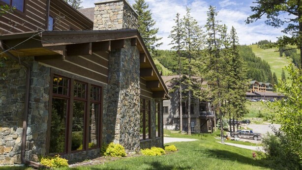 A lodge with stone walls, large windows, and a covered porch. - Hotel Style Room Near Slopes (Whitefish)