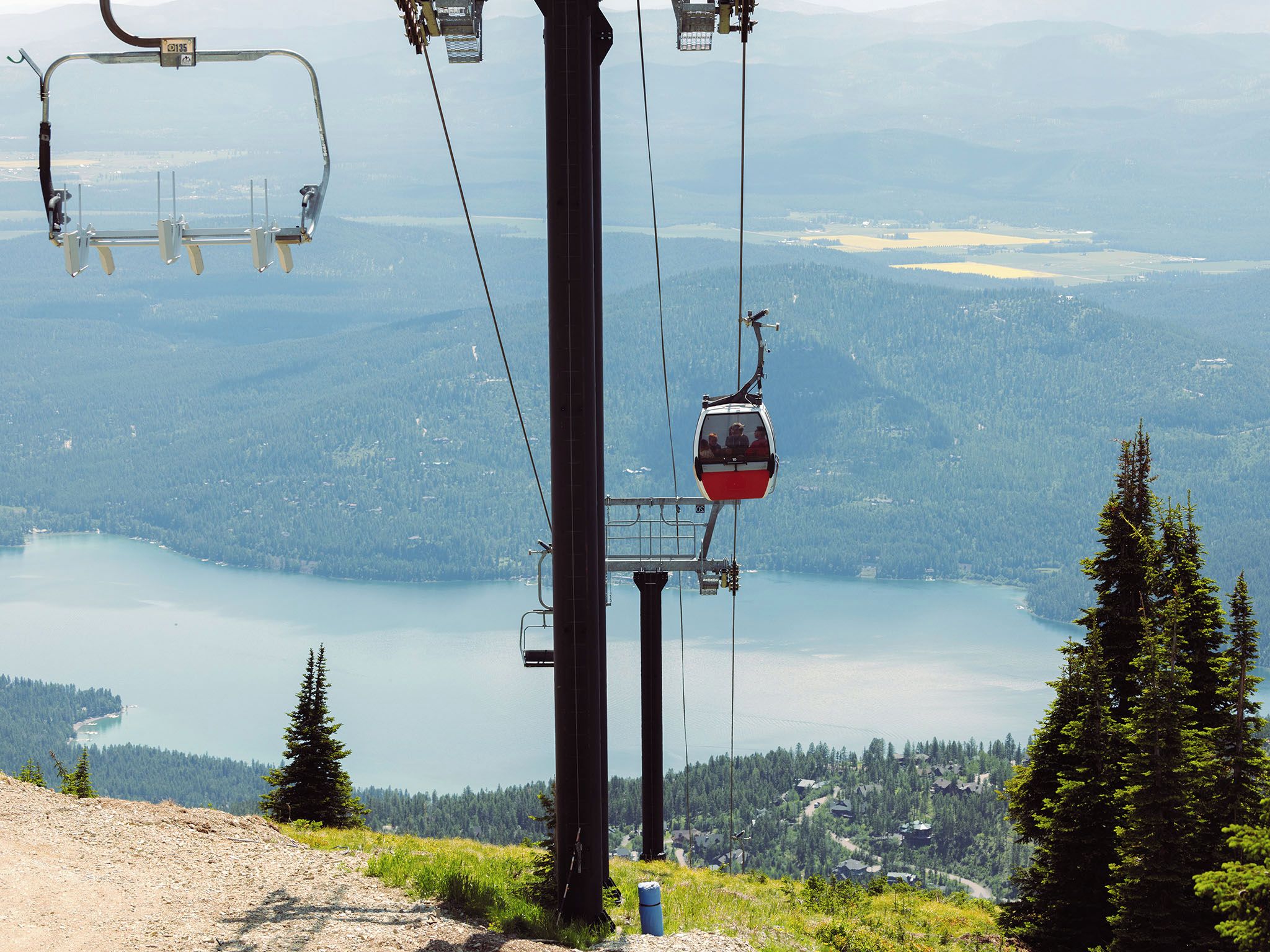 A cable car system with a lake and forested landscape in the background.