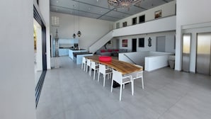 Un interior espacioso y moderno con zona de comedor central, cocina y sala de estar.