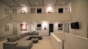 Amplia sala de estar con un sofá seccional en forma de L, una mesa de centro redonda y un televisor de pantalla plana montado en la pared.