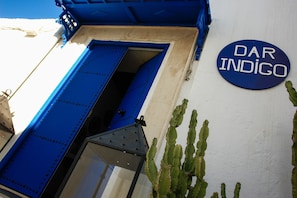 A building entrance with a blue door and a sign that reads "DAR INDIGO".