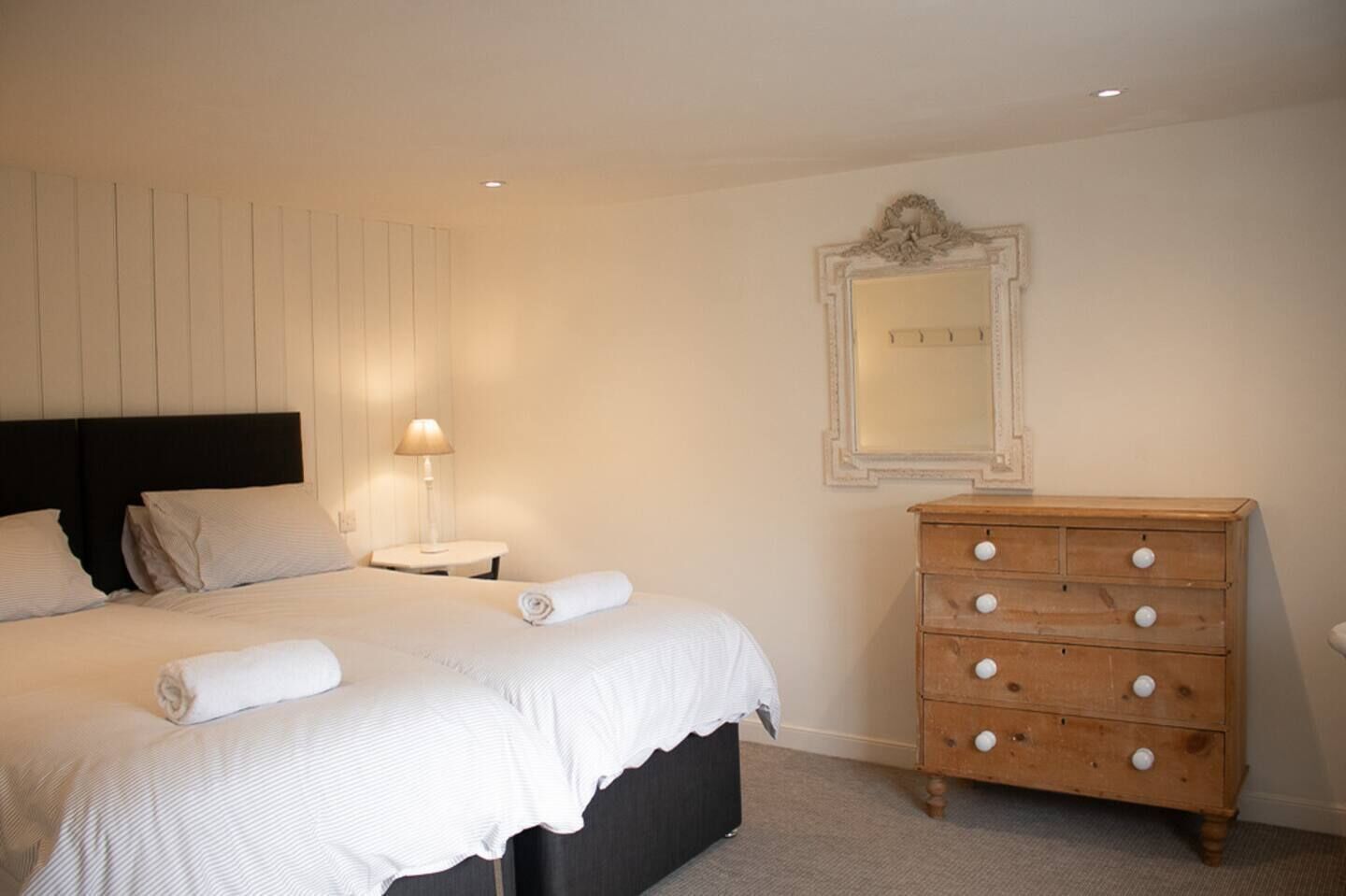 A bedroom with a bed, a nightstand, a dresser, and a mirror.