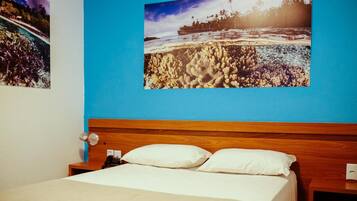 Una habitación de hotel con una cama, una mesita de noche y una pared con dos cuadros enmarcados.