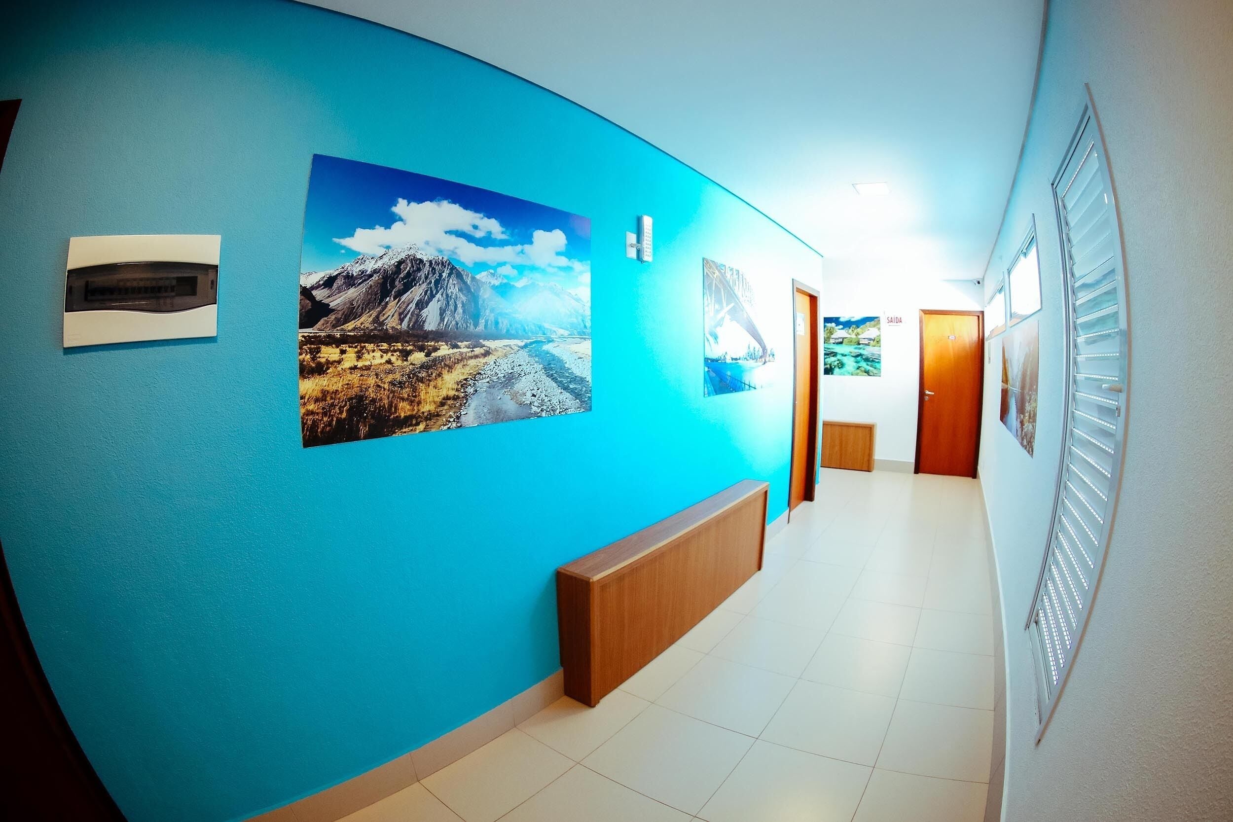 Um corredor com parede azul, um banco de madeira e quadros emoldurados.