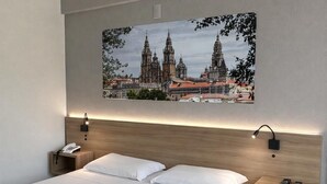 A modern hotel room with a large bed, two bedside tables, a nightstand, a wall-mounted lamp, and a framed cityscape picture. - Rede Andrade Criciúma (Criciuma)