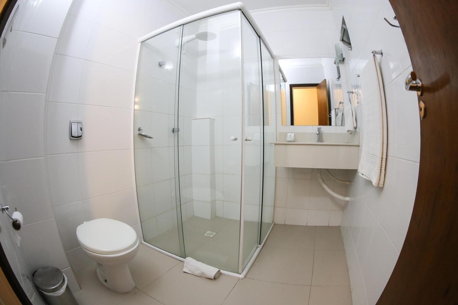Un baño con cabina de ducha de vidrio, inodoro y lavamanos con espejo.