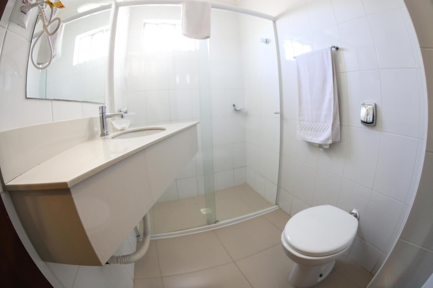 A modern bathroom with a glass-enclosed shower, a white sink, and a toilet.