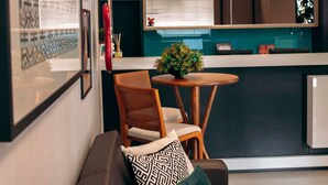 A modern living room with a sofa, a small table, and a kitchen area in the background. - Rede Andrade Criciúma (Criciuma)