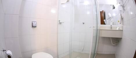 A modern bathroom with a glass-enclosed shower, a toilet, and a sink with a mirror.