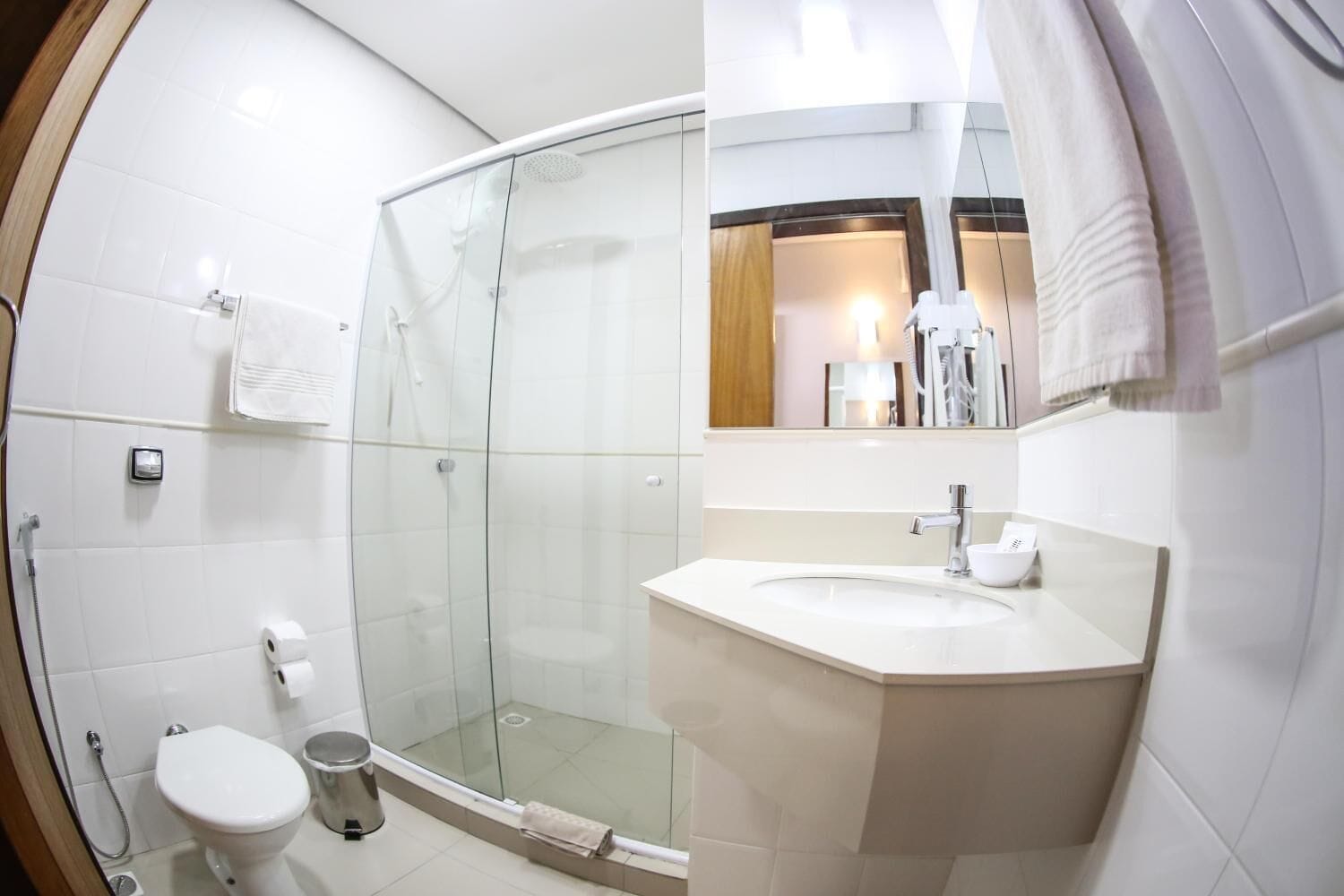 Ein modernes Badezimmer mit einer gläsernen Dusche, einem weißen Waschbecken und einer Toilette.