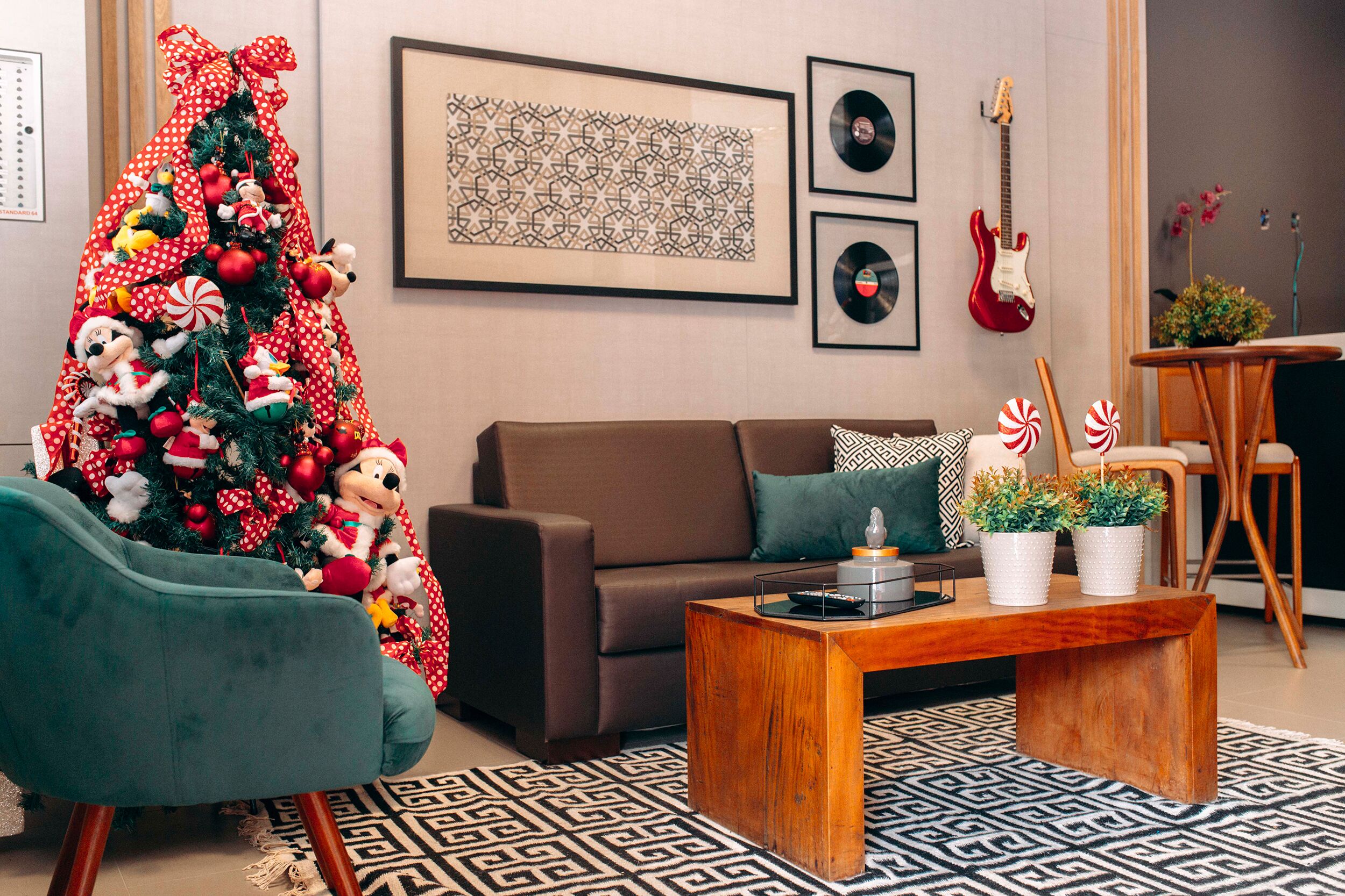 A living room with a Christmas tree, a brown sofa, a wooden coffee table, and a patterned rug.