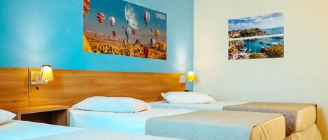 A hotel room with three beds, a wooden headboard, and two wall-mounted lamps.