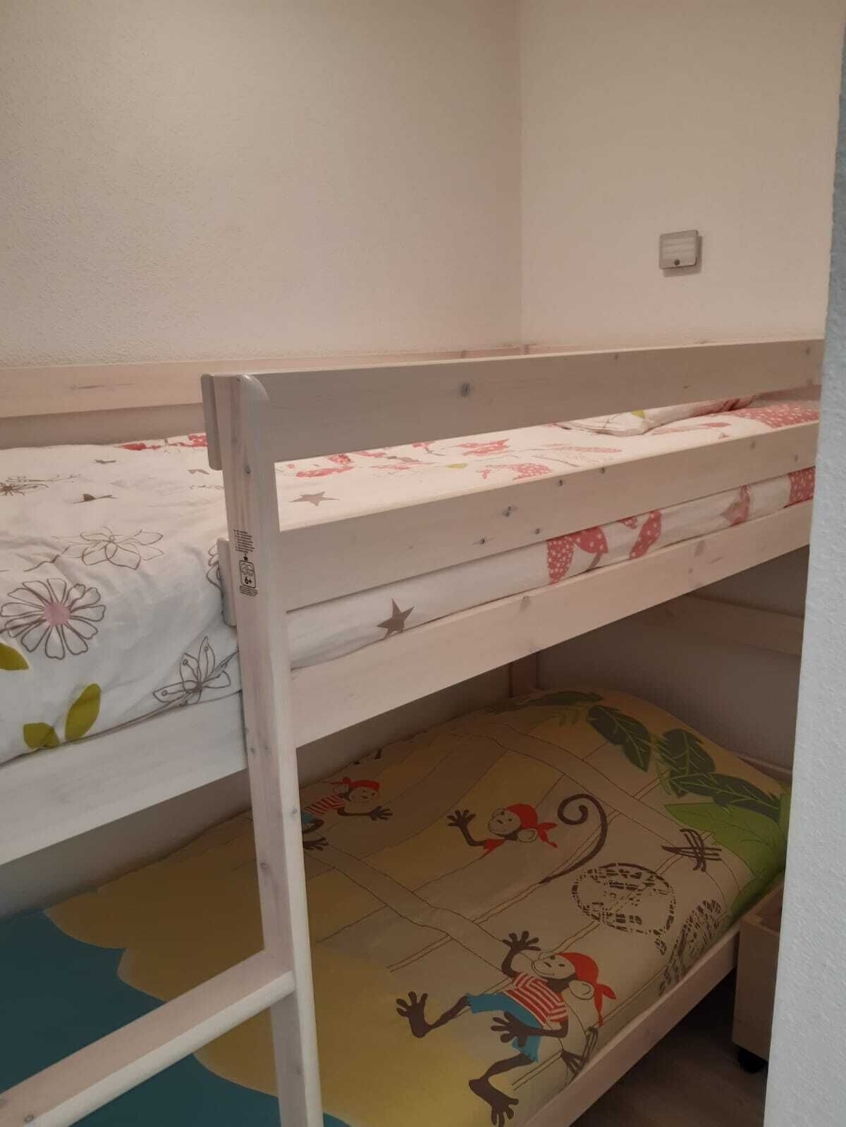 A bunk bed with floral bedding and a cartoon-themed mat.