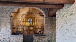 A stone-walled room with a barred window, a stone bench, and a cobblestone floor. - Beautiful apartment 6pers valfrejus the great financier. (valfrejus)