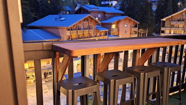 A terrace with wooden furniture and a view of mountain houses. - Beautiful apartment 6pers valfrejus the great financier. (valfrejus)