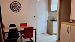 A modern living room with a wooden dining table, red chairs, and a brown sofa. There is a kitchen area visible in the background with wooden cabinets and a countertop. - Beautiful apartment 6pers valfrejus the great financier. (valfrejus)