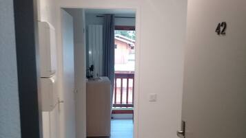 Ein Flur mit Holzboden, der zu einem Zimmer mit Balkon führt.
