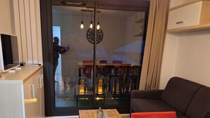 A modern living space with a wooden dining table, a sofa, and a kitchen area with a TV. - Beautiful apartment 6pers valfrejus the great financier. (valfrejus)