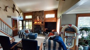 Ein geräumiges Wohnzimmer mit Kamin aus Stein, einer alten Jukebox und einer Treppe zu einer weiteren Ebene.