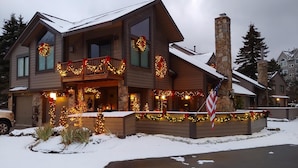 Ein zweistöckiges Haus mit Balkon, geschmückt mit Weihnachtsbeleuchtung und Girlanden.