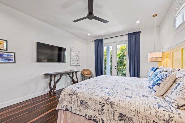 A bedroom with a bed, a television, a table, and a chair.