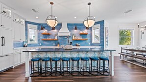 A modern kitchen with a central island, bar stools, and pendant lighting.