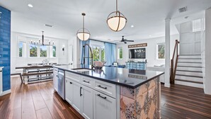A spacious kitchen with a large island, white cabinetry, and a blue accent wall.