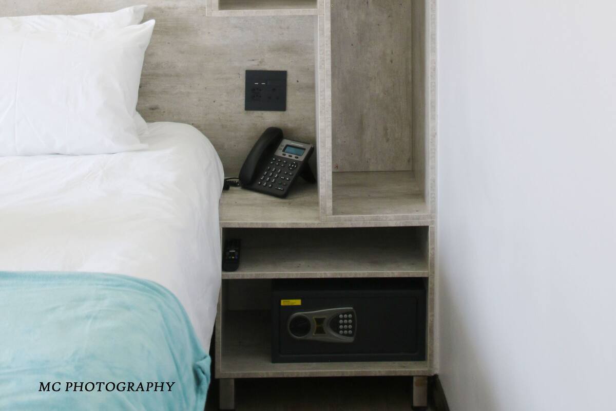 A bedroom with a bed, a wardrobe, and a telephone.