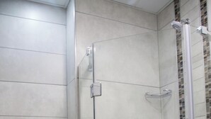 A bathroom with a glass-enclosed shower, a toilet, and a sink.