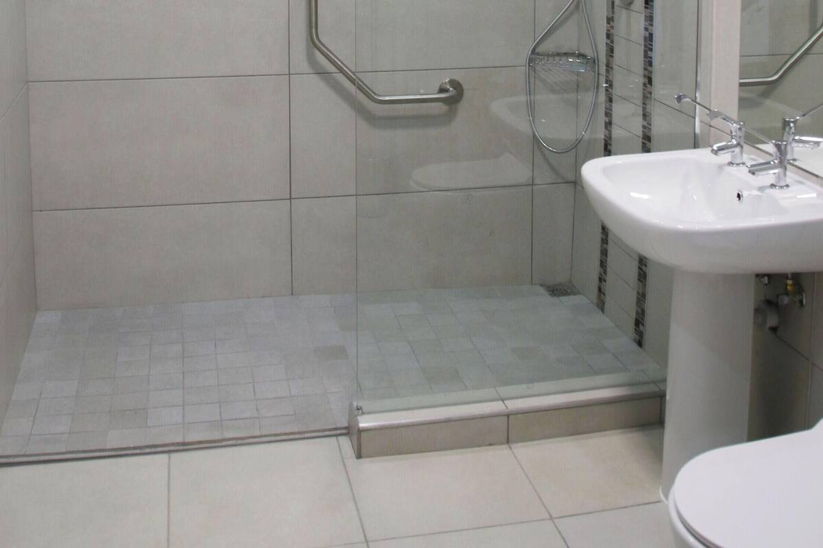 A bathroom with a shower, a sink, and a toilet.