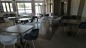 A spacious indoor area with multiple tables and chairs arranged for dining or meetings.
