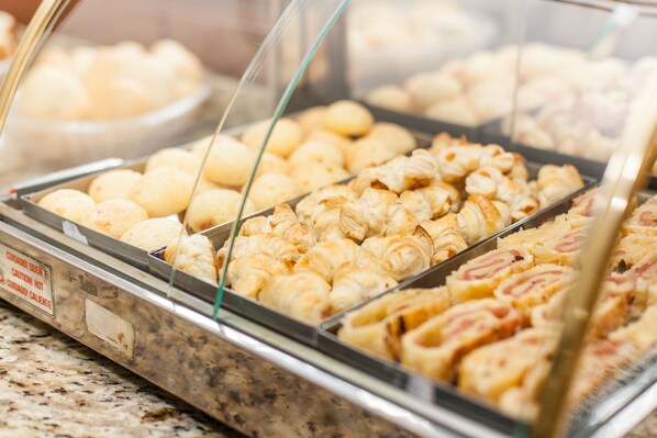 Una vitrina con diversas opciones de panadería, incluyendo pasteles y pan.