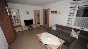 Un salon avec un canapé, une table basse, un téléviseur et une bibliothèque.