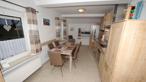 Un coin repas avec une table dressée pour six personnes, une fenêtre avec des rideaux et des meubles en bois.
