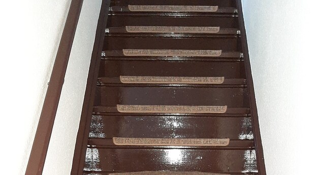 Un escalier en bois avec des marches recouvertes d’un tapis tissé.