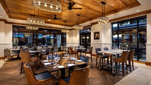 A restaurant with wooden ceiling, chandeliers, and large windows. Tables are set with wine glasses and plates. - Brownwood Hotel & Spa (Wildwood)