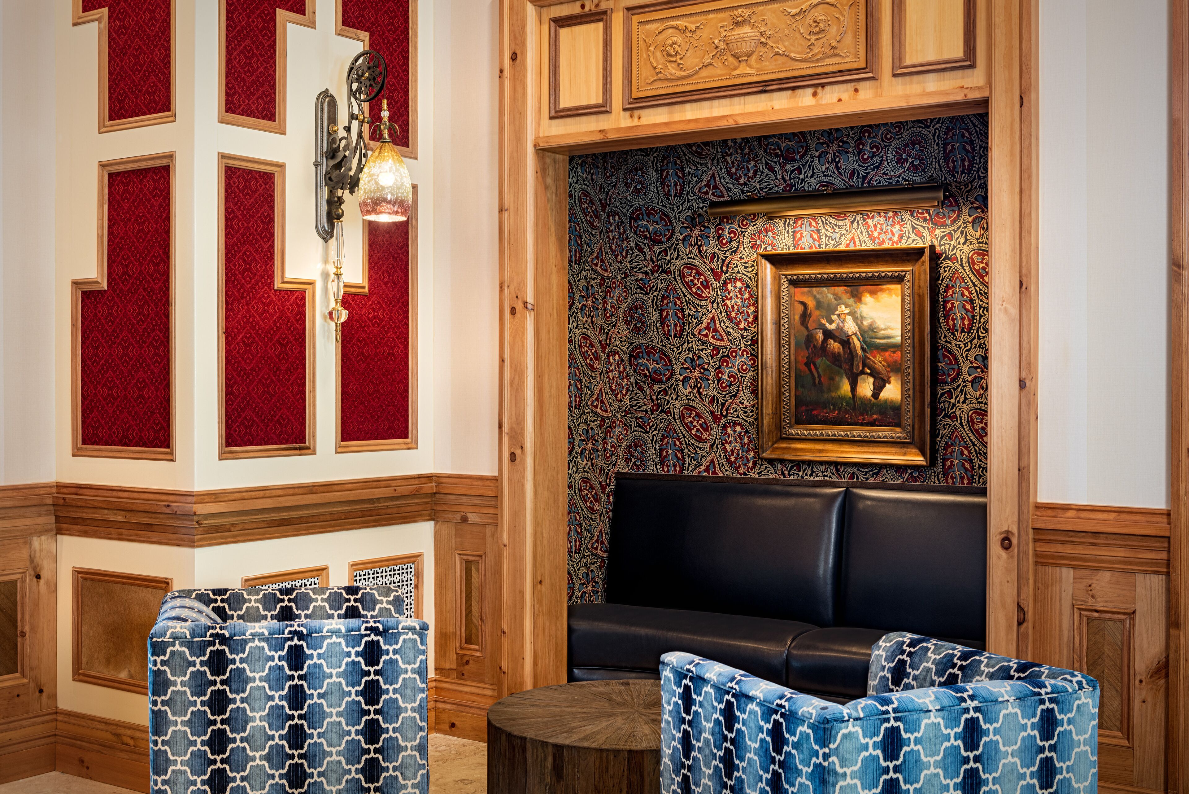 A room with a patterned wall, a black leather sofa, and patterned chairs.